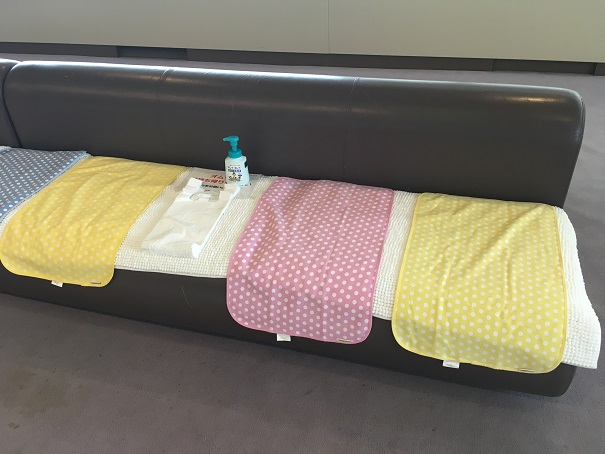 しまじろうコンサート2019夏の高松公演の会場内にあるおむつ替えスペースの様子、防水シーツと袋と消毒液がソファーの上に並べられている
